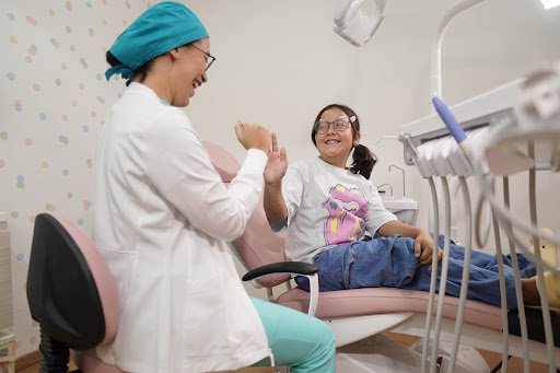 Dra. Edith González celebrando con una paciente infantil en el sillón dental de ortodoncia
